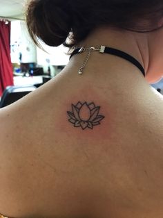 the back of a woman's neck with a lotus tattoo on it