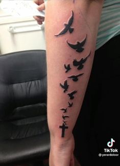 a person with a cross and birds tattoo on their arm