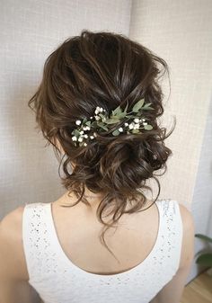 a woman wearing a white tank top with flowers in her hair