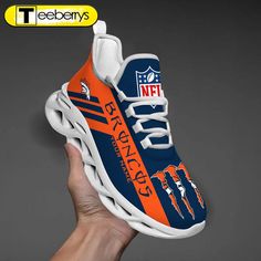 a hand holding up a sneaker that has the nfl logo on it and an orange stripe