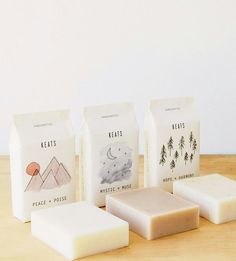 three soap bars, one white and one brown on a wooden table with mountains in the background