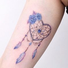 a woman's arm with a tattoo on it that has blue roses and a dream catcher