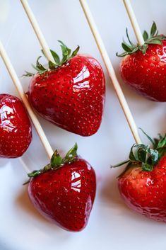 strawberries are arranged on toothpicks with green leaves