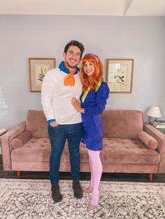 a man and woman standing next to each other in front of a couch with pink furniture