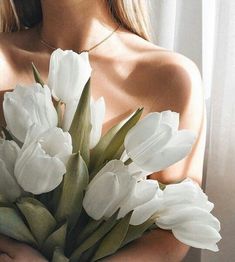 a woman holding a bouquet of white tulips