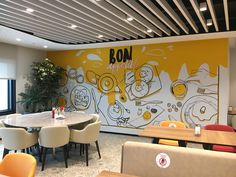 an empty restaurant with tables and chairs in front of a wall painted with cartoon characters