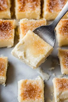 a spoon with sugar on top of small squares of cake