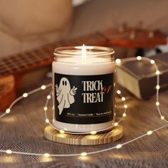 a white candle sitting on top of a wooden table next to a string of lights