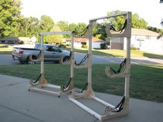 two wooden frames sitting on the side of a road next to a parked car in front of a house