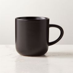 a black coffee cup sitting on top of a white counter