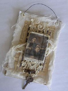 an old photo hanging on a piece of fabric with a key attached to the back