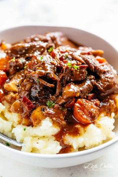 a close up of a bowl of food with mashed potatoes and beef on it