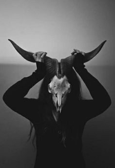 a woman with horns on her head is standing in front of the camera and wearing a horned mask