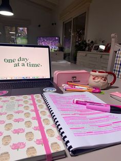 an open laptop computer sitting on top of a desk next to a notebook and pen