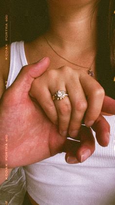 a close up of a person holding the hand of another person with an engagement ring on their finger