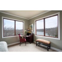 a bedroom with two large windows and a bench