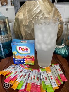 a glass filled with ice sitting on top of a wooden table next to a pile of packets