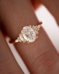 a woman's hand with a three stone diamond ring on her left hand and the other hand holding an engagement ring