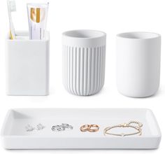 white bathroom accessories including toothbrush holder, soap dispenser and bracelets