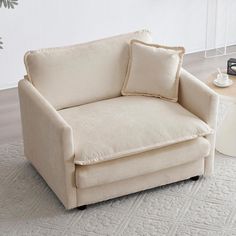 a white couch sitting on top of a rug next to a table