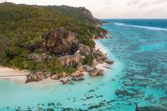 an aerial view of the beach and ocean with many rocks, trees, and water