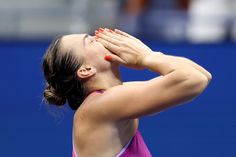 a female tennis player wiping her face with her hands on the side of her head