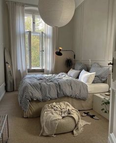 a bedroom with a large bed and lots of pillows on the floor next to a window