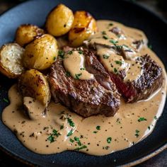 a steak with gravy and potatoes on a black plate, ready to be eaten