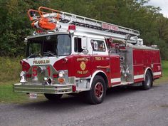 a red fire truck is parked on the side of the road with trees in the background