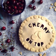 a cherry pie sitting on top of a table next to cherries