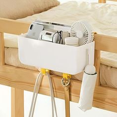 a bed with a fan and other items in it on the bottom bunk rail next to a pillow