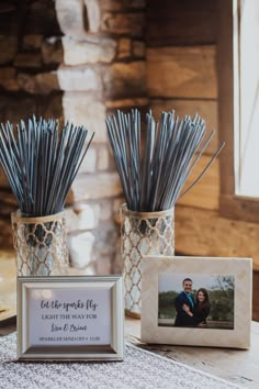 two vases with sticks in them sitting on a table next to a photo frame