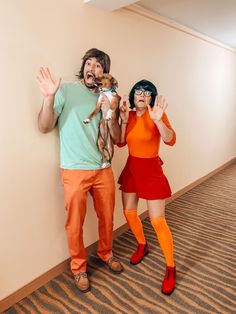 two people dressed in costumes posing for a photo with a cat on their shoulders and hands up