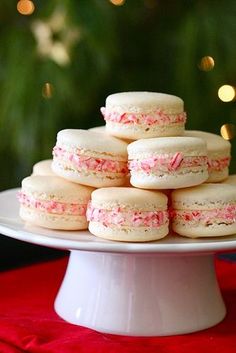 a stack of pink and white macaroons sitting on top of each other in front of a christmas tree