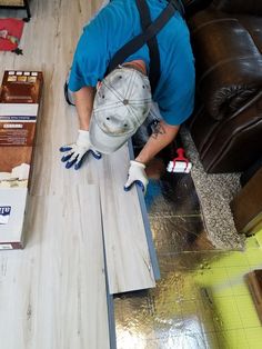 a man laying on the floor working on some wood planks in a room with other items