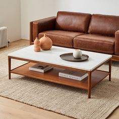 a living room with a couch, coffee table and books on the floor in front of it