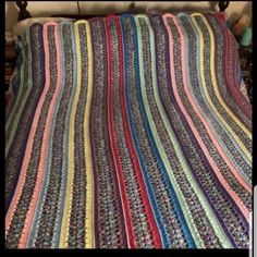 a crocheted blanket that is laying on a bed with the cover pulled down