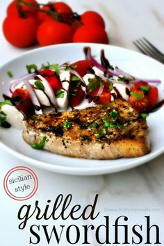 grilled swordfish with tomatoes and onions on a white plate