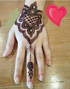 a henna tattoo on someone's hand next to a heart shaped pink object