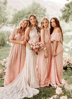 four bridesmaids pose for a photo in front of pink flowers and greenery