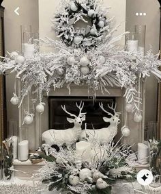 a fireplace decorated for christmas with white decorations and deer heads on it's mantle