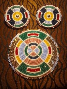 two colorful beaded coasters sitting on top of a table