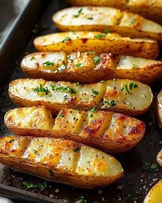 baked potatoes on a baking sheet with parmesan cheese and herbs sprinkled on top