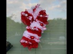 a red and white wreath hanging on the side of a window