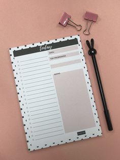 a notepad, pen and clipboard on a pink surface