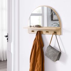 a mirror, coat rack and purse hanging on a wall in a room with white walls