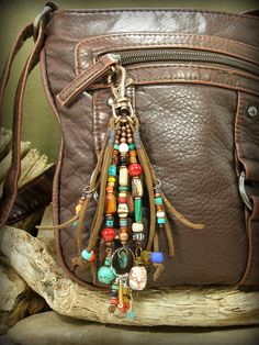 a brown leather purse with multi - colored beads hanging from it