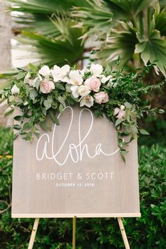 a wooden sign with flowers and greenery on it