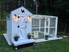 a small white chicken coop with lights on