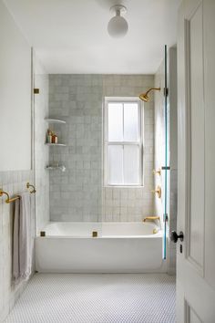 a bathroom with white tile and gold fixtures